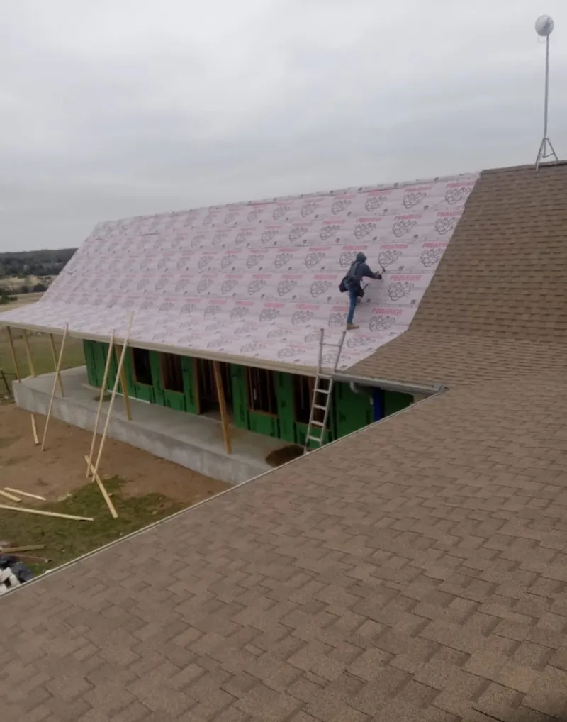 Worker preparing underlayment for a metal roof installation in Franklin
